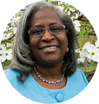 Portrait of Florence A. Hill-Trent smiling outdoors in front of a flowering dogwood